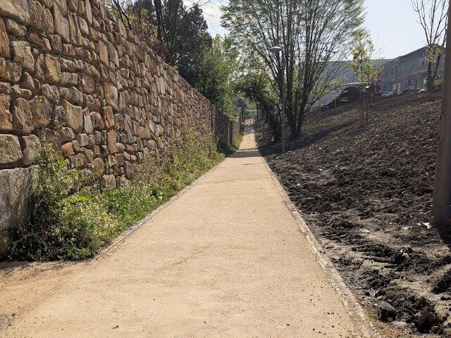 Sendero peatonal estabilizado junto a un muro de piedra