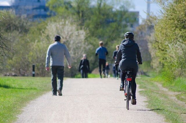Peatones y ciclistas en un paseo urbano de pavimento terrizo