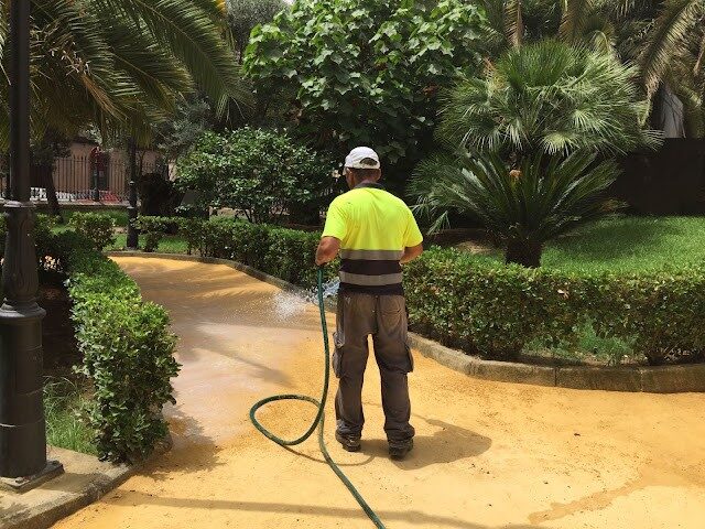 Operario aplicando tratamiento de riego sobre pavimento terrizo