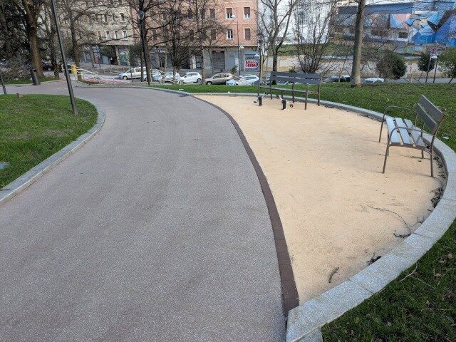 Paseo de parque con pavimento terrizo y mobiliario urbano